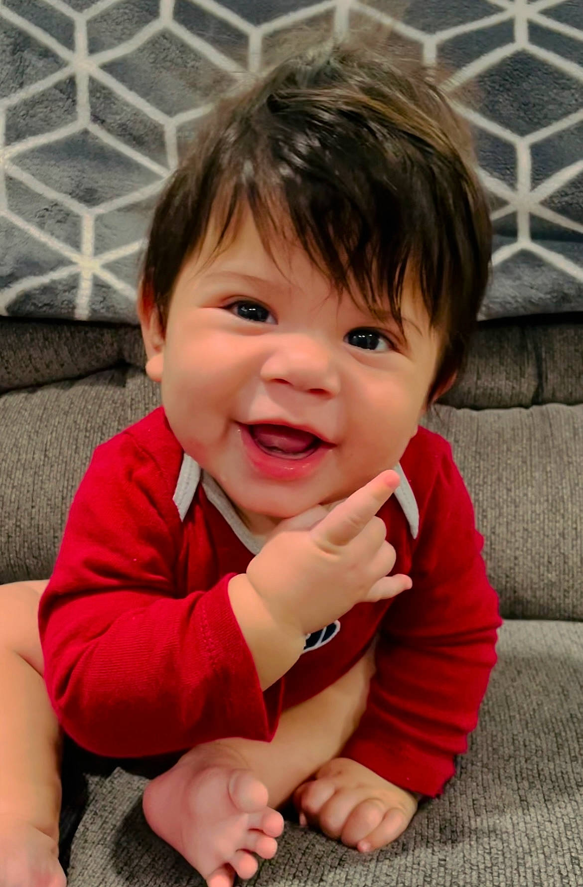 Emilio is registered to the contest to win money with this photo: arm, baby_toddler_clothing, cheek, chin, eyebrow, face, finger, flooring, gesture, hand, happy, iris, lip, nose, person, pink, skin, sleeve, smile, thumb