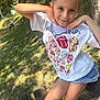 Malia a rejoint le concours — aidez-le/la à gagner de superbes lots ! child, girl, smiling, posing, tshirt, denim_shorts, outdoor, bench, grass, trees, sunlight, nature, playful, happy, summer, casual_clothing, park, person, portrait, daylight