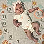 baby, infant, child, milestone_blanket, pink_bow, onesie, flower_print, months, age_marker, cute, lying_down, pout, pastel_colors, soft_texture, skin, hand, foot, headband, portrait, indoor