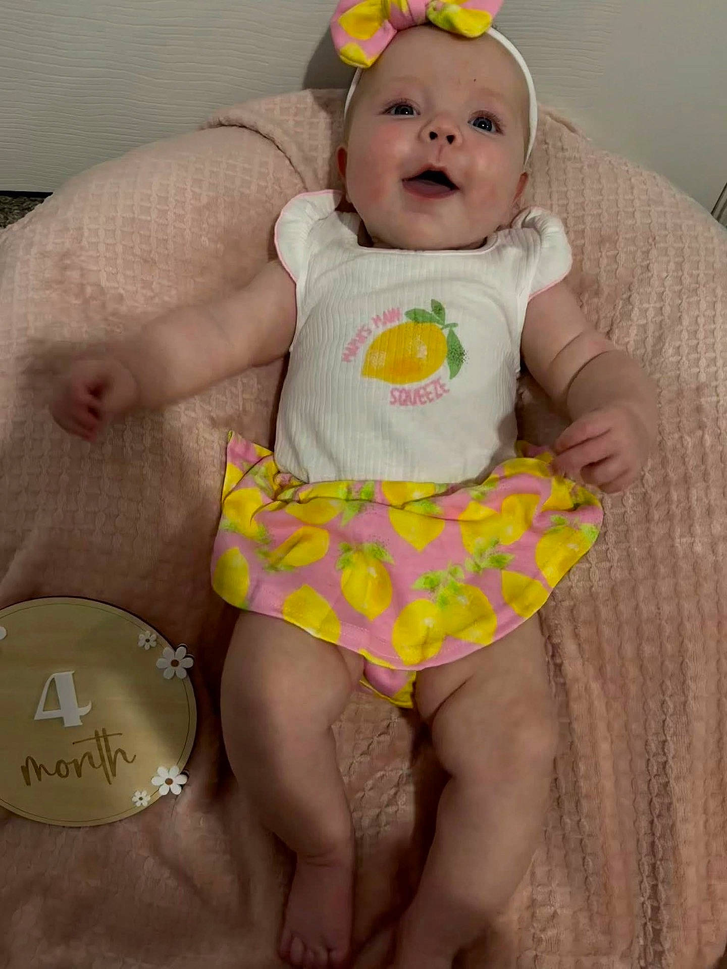 4_month, arms, baby, child, clothing, cute, happy, head, headband, indoors, infant, legs, lemon_pattern, lying_down, milestone_marker, person, pink_blanket, skin, smiling, soft_texture