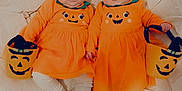 Manaé Et Judith a rejoint le concours — aidez-le/la à gagner de superbes lots ! baby, twins, infant, orange_dress, pumpkin_face, halloween, costume, bucket, cute, toddler, lying_down, cushion, soft, face, child, smile, indoors, holiday, festive, holding
