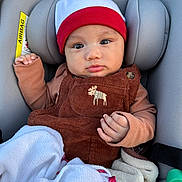 Teahinuiarii participe au concours pour gagner de l'argent avec cette photo : baby, infant, car_seat, beanie, red_hat, brown_overalls, corduroy, embroidered_moose, blanket, hand, face, eyes, cheeks, headrest, seat_padding, safety_label, clothing, portrait, cozy, cute