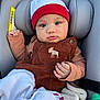 baby, infant, car_seat, beanie, red_hat, brown_overalls, corduroy, embroidered_moose, blanket, hand, face, eyes, cheeks, headrest, seat_padding, safety_label, clothing, portrait, cozy, cute