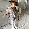 Linaya a rejoint le concours — aidez-le/la à gagner de superbes lots ! child, clothing, couch, door, girl, hair_buns, interior, living_room, overalls, pillow, portrait, pose, smile, sofa, standing, striped_tights, tiled_floor, toddler, white_shoes, wood_paneling