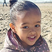 Linaya participe au concours pour gagner de l'argent avec cette photo : beach, child, close_up, coat, earring, girl, hair_bun, happy, horizon, jacket, ocean, person_in_background, polka_dots, portrait, sand, smile, sunlight, teeth, walking, waves