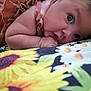 Kira is registered to the contest to win money with this photo: baby, infant, face, hand, flower_pattern, blanket, skin, clothing, cute, lying_down, closeup, portrait, child, young, indoors, soft_light, expression, resting, comfort, toddler