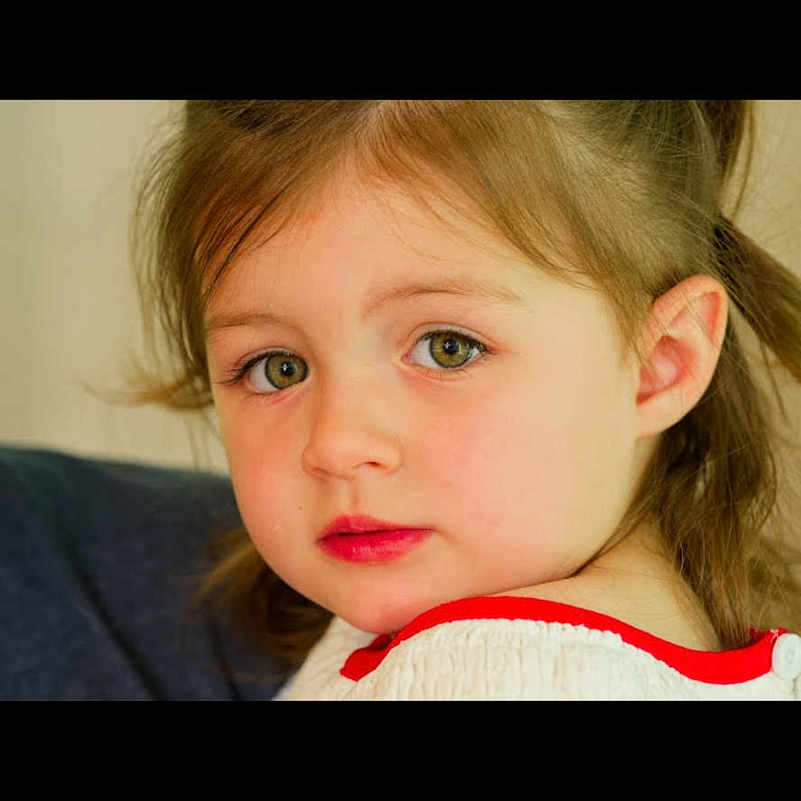 Ivy Rose joined the competition — help win amazing prizes! child, close_up, clothing, expression, eyebrows, eyelashes, face, green_eyes, hair, indoors, looking_back, person, portrait, red_trim, rosy_cheeks, skin, soft_light, warm_tones, white_top, young_child