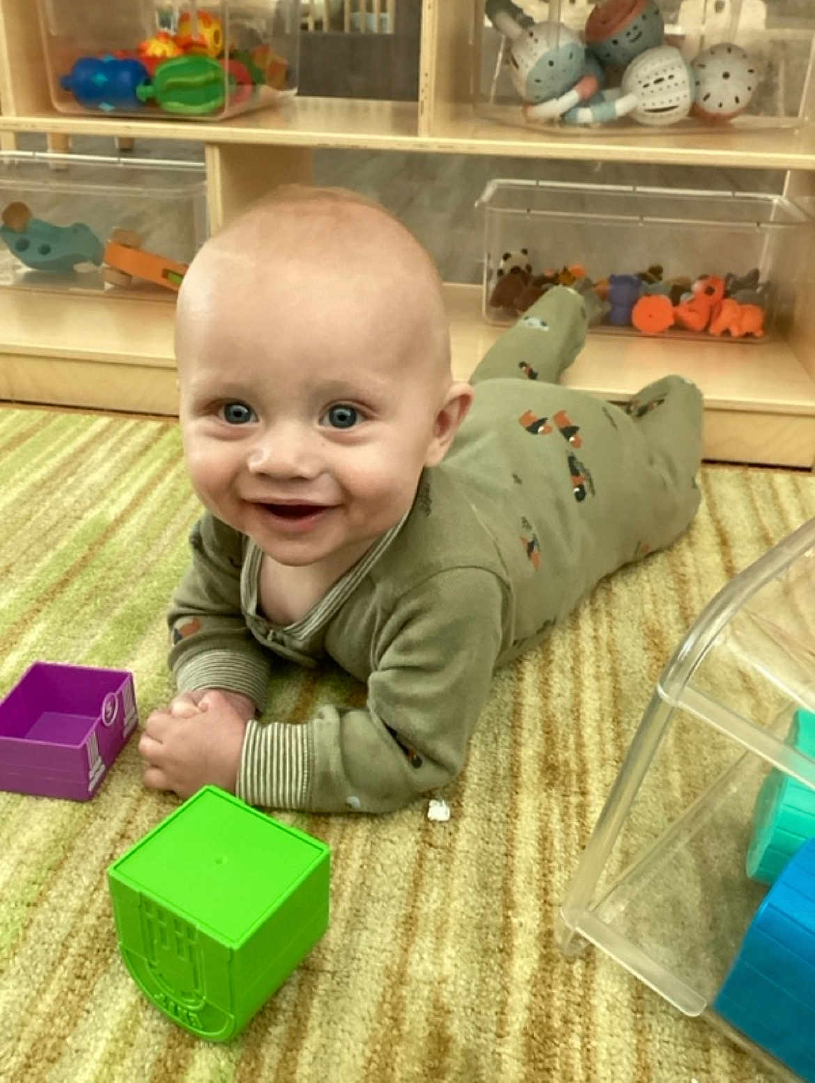 Michal joined the competition — help win amazing prizes! baby, infant, pajamas, carpet, toy, block, smile, face, floor, child, indoor, playtime, shelf, container, colorful, furniture, cute, happy, person, room