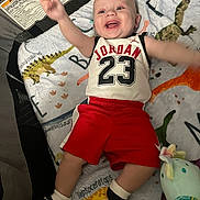 Michal joined the competition — help win amazing prizes! baby, infant, smiling, jordan, sportswear, red_shorts, black_socks, blanket, dinosaur_pattern, toy, lying_down, happy, cute, child, indoor, playpen, colorful, soft_texture, cheerful, casual_clothing