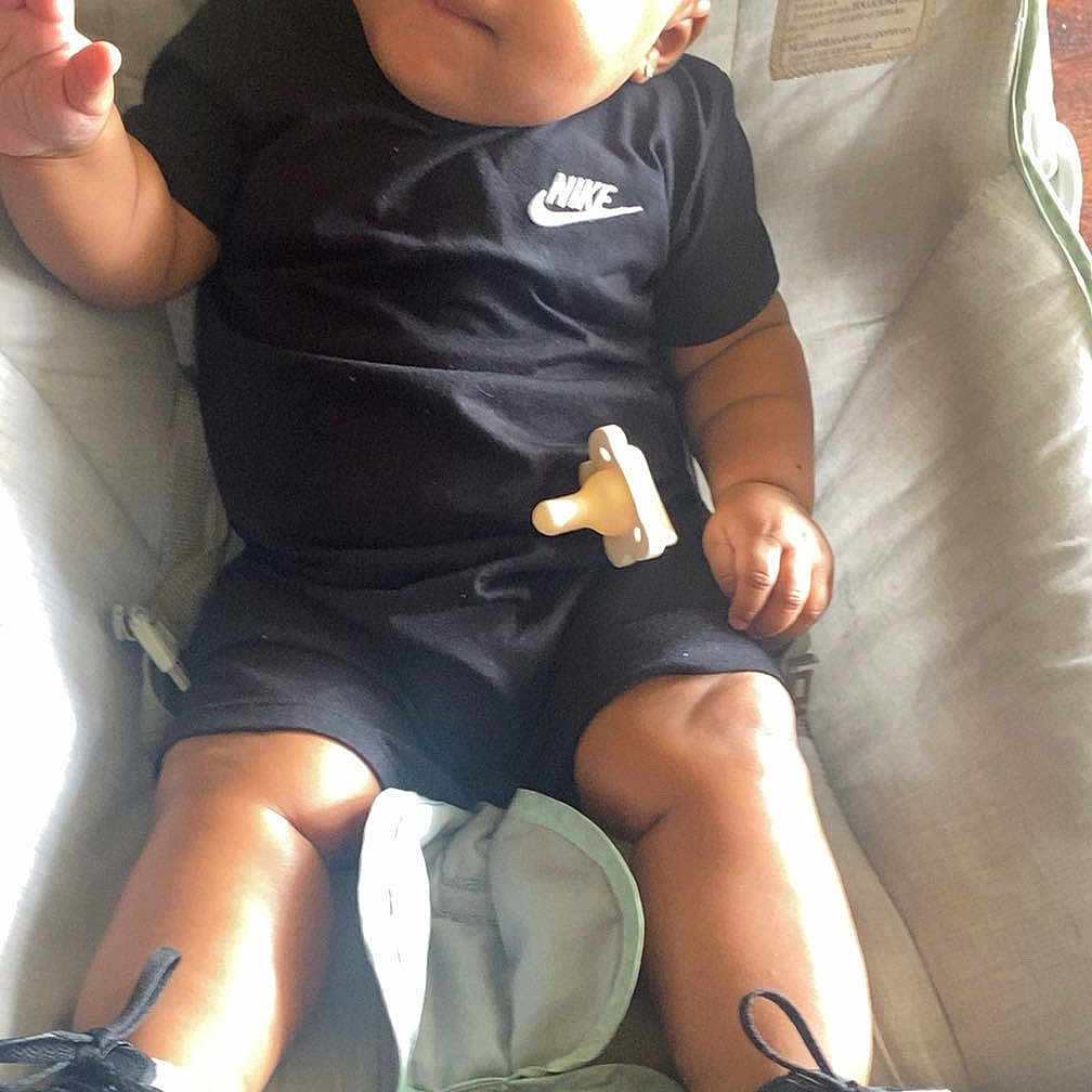 Da joined the competition — help win amazing prizes! baby, infant, child, nike, black_clothing, sneakers, pacifier, baby_seat, cushion, indoor, floor, wood_floor, relaxed, cute, smiling, portrait, person, footwear, comfortable, casual