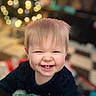 baby, bangs, blanket, blonde_hair, bokeh_lights, cheeks, child, christmas_tree, cozy, cute, eyes_squinting, face, happiness, holiday_decor, indoor, playmat, portrait, smile, toddler, toothy_grin