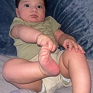 Jaden is registered to the contest to win money with this photo: baby, child, infant, foot, hand, onesie, green_clothing, cushion, blue_background, cute, pout, wide_eyes, skin, soft_texture, lying_down, indoor, person, playful, chubby_cheeks, adorable
