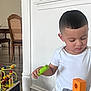 Jaden is registered to the contest to win money with this photo: child, toddler, white_shirt, wooden_block, toy, indoor, floor, table, furniture, decor, wooden_chair, play, concentration, short_hair, person, home, colorful, activity, learning, casual_clothing