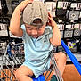 Jaden joined the competition — help win amazing prizes! toddler, child, shopping_cart, cap, blue_outfit, sneakers, green_socks, bracelet, store_aisle, home_goods, curtains, metal_cart, playful, cute, indoor, person, clothing, footwear, retail, smiling