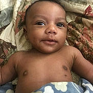 Kyrie is registered to the contest to win money with this photo: baby, infant, child, face, eyes, smile, blanket, quilt, pattern, cloud, star, skin, arm, torso, bed, comfort, rest, cute, portrait, indoors