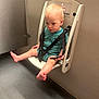 toddler, child, baby, safety_seat, wall_mounted, straps, barefoot, curious, indoor, floor, hair, clothing, onesie, seat, neutral_colors, expression, small_feet, plastic, room, childcare