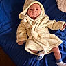 baby, infant, robe, hood, bed, blanket, blue_bedspread, sock, lying_down, indoor, person, clothing, cute, soft_texture, sleepwear, newborn, calm, portrait, child, babywear