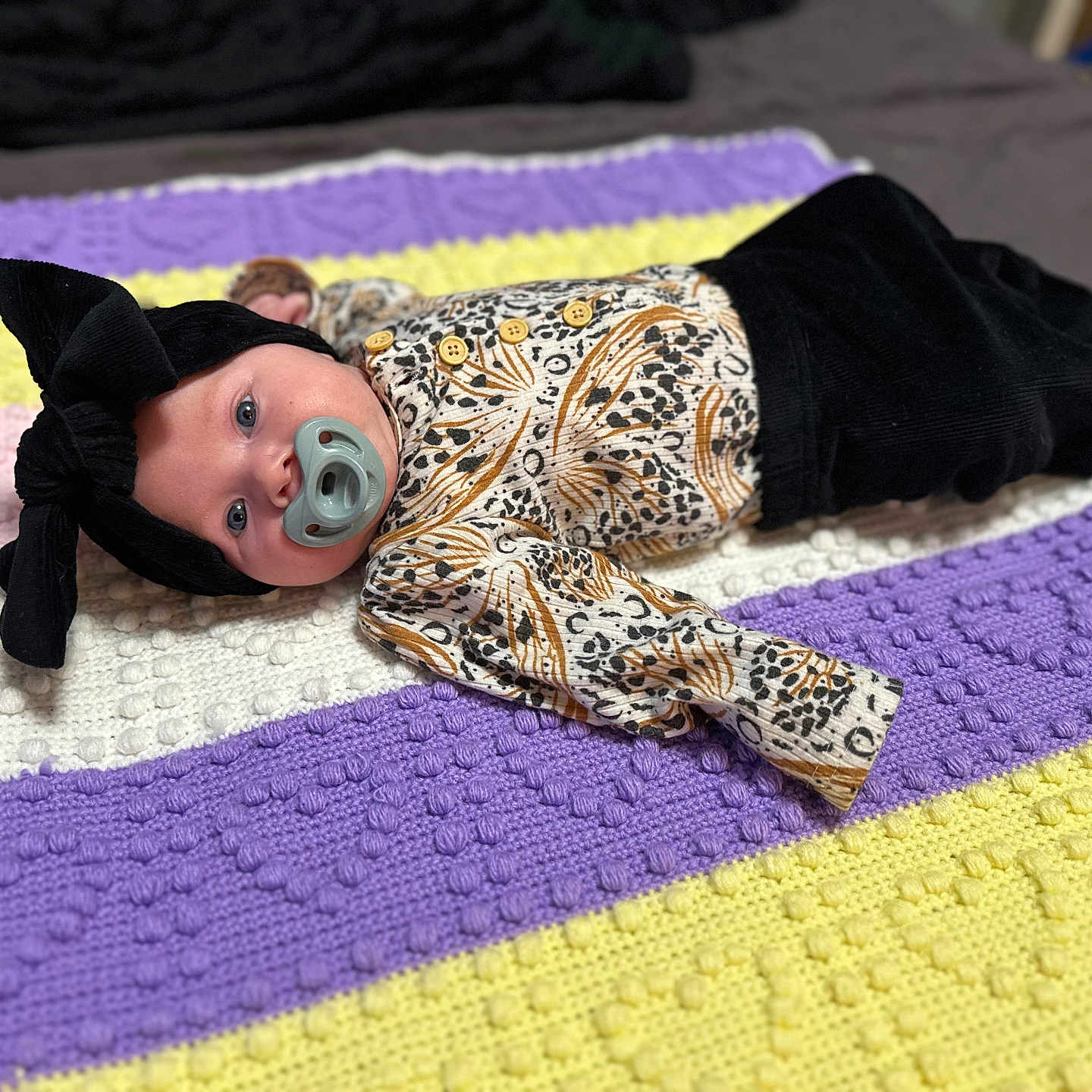 Lorelei joined the competition — help win amazing prizes! baby, black_bow, blanket, child, colorful, cozy, cute, headband, indoor, infant, knitted, looking_at_camera, lying_down, pacifier, patterned_clothing, portrait, small_person, soft_texture, striped_blanket, young_child