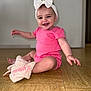 baby, child, smiling, pink_clothing, headband, bow, indoor, floor, plush_toy, happy, cute, sitting, portrait, person, infant, accessory, jewelry, earrings, wooden_floor, door