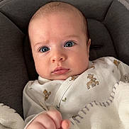 Tiam participe au concours pour gagner de l'argent avec cette photo : baby, infant, blanket, onesie, giraffe_pattern, blue_eyes, cute, cozy, hand, fist, portrait, closeup, indoor, soft, child, young, face, expression, person, seated