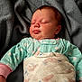 baby, sleeping, blanket, pajamas, polka_dot, face, hand, infant, resting, soft_texture, cozy, child, cute, newborn, peaceful, skin, head, lying_down, indoors, comfort