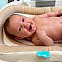 baby, infant, smile, face, skin, hand, bath, bathroom, cushion, soft, cute, happy, lying_down, child, newborn, water, expression, indoors, closeup, person