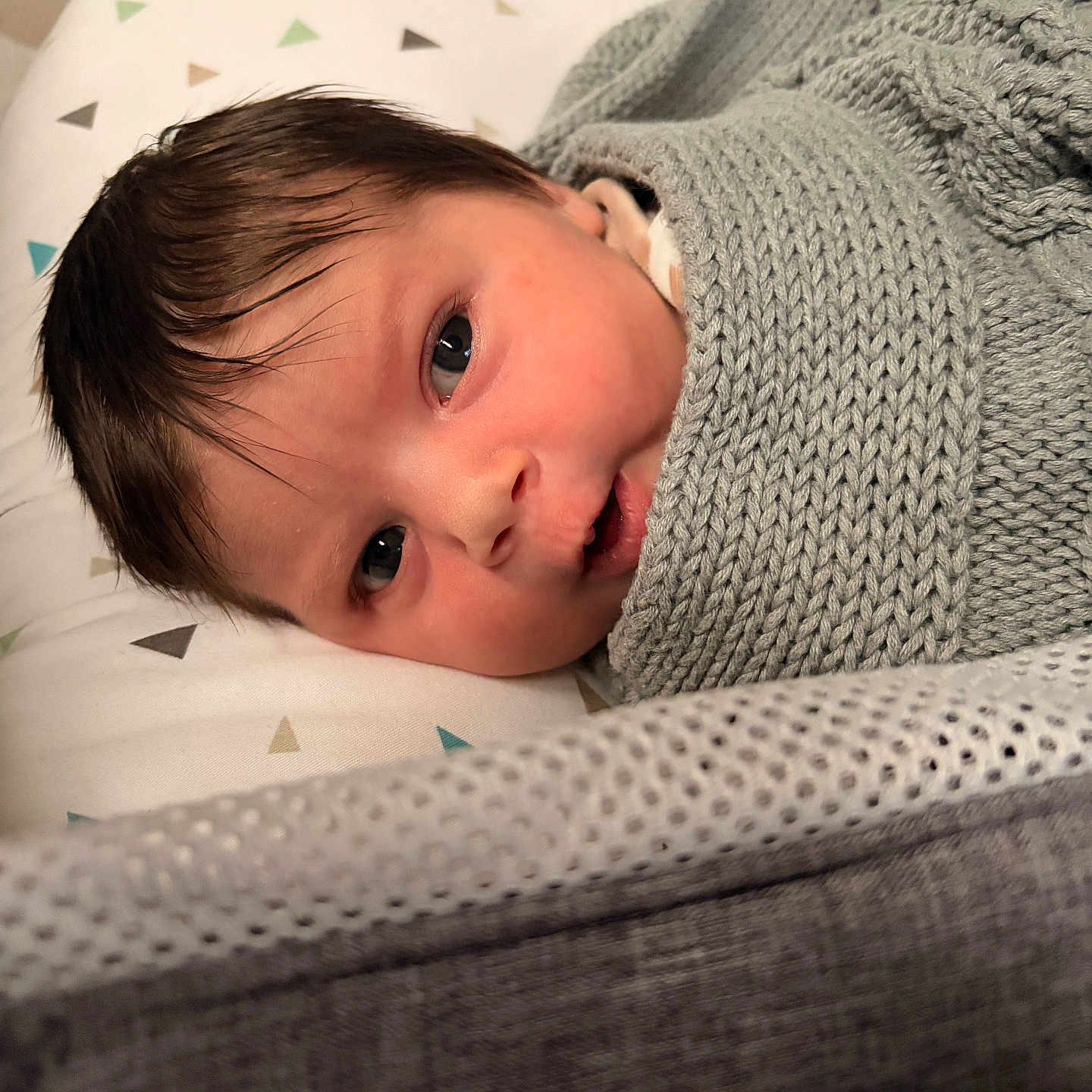Sage is registered to the contest to win money with this photo: baby, bed, blanket, blue_eyes, cozy, cute, face, hair, indoors, infant, knitwear, lying_down, newborn, pattern, person, pillow, skin, sleeping_area, soft_texture, triangle