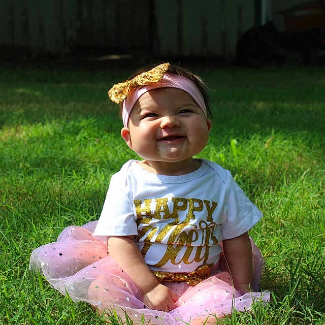 Carmen is registered to the contest to win money with this photo: backyard, ball, clothing, face, football, grass, head, lawn, nature, outdoors, person, photography, plant, portrait, sitting, soccer, soccerball, sport, t_shirt, yard