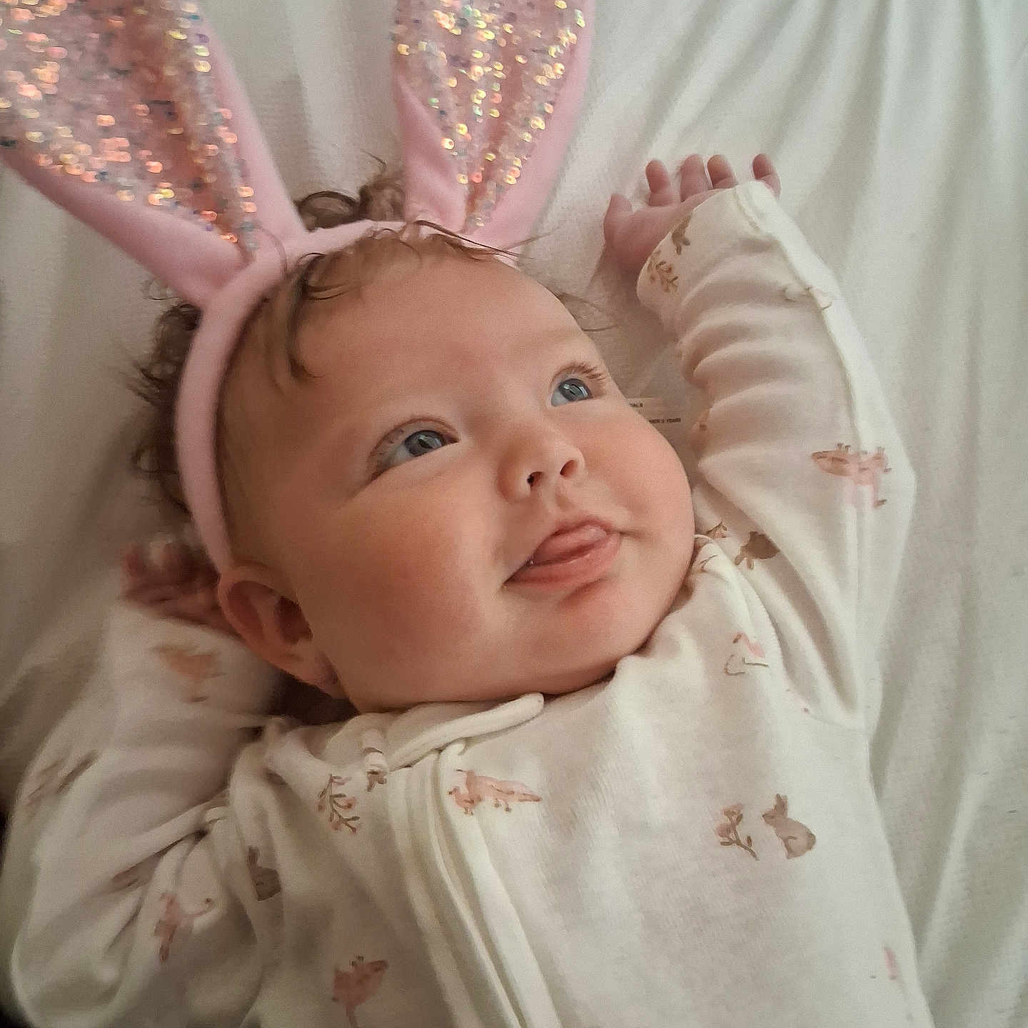 Kaselynn joined the competition — help win amazing prizes! baby, bunny_ears, onesie, infant, cute, playful, lying_down, blue_eyes, sparkly, pink, white_sheet, animal_prints, tongue_out, soft_lighting, child, portrait, indoor, sleepwear, headband, smiling