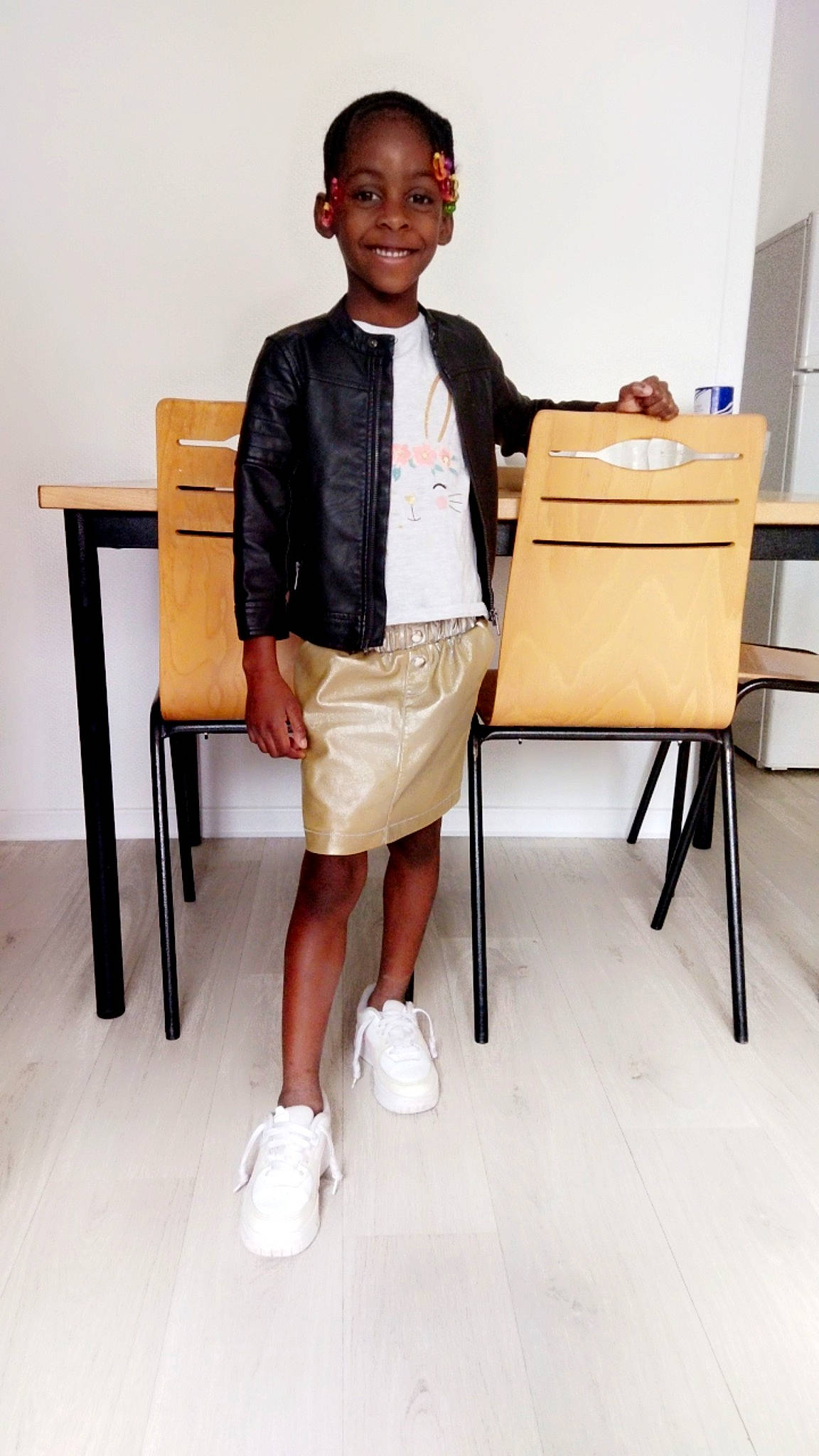 Emmanuella a rejoint le concours — aidez-le/la à gagner de superbes lots ! chair, collar, dress_shirt, event, fashion_design, flooring, formal_wear, happy, job, joint, joy, person, room, school_uniform, sitting, sleeve, smile, t_shirt, table, toddler