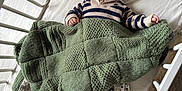 Arthur a rejoint le concours — aidez-le/la à gagner de superbes lots ! baby, crib, blanket, knitted_blanket, striped_sweater, smiling, infant, bed, sleepwear, wooden_crib, child, happy, indoors, face, person, cute, resting, playful, soft_texture, cozy