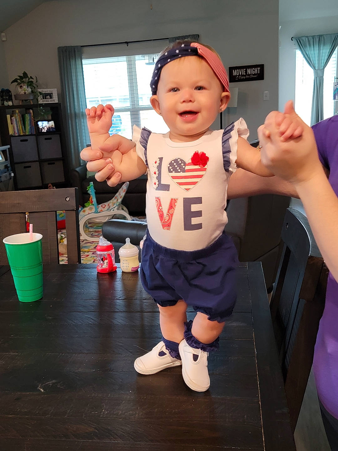 Margaret is registered to the contest to win money with this photo: arm, baby, carmine, child, costume, fictional_character, fun, gesture, hand, happy, hat, headwear, human_leg, joy, mascot, person, room, shorts, sleeve, smile