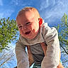 baby, child, smiling, happy, outdoor, sky, blue_sky, trees, greenery, hands, tattoos, clothing, long_sleeve, infant, person, portrait, cute, daylight, nature, joy
