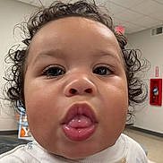 Akari joined the competition — help win amazing prizes! baby, infant, child, portrait, close_up, face, curly_hair, tongue, serious_expression, looking_at_camera, indoor, ceiling_lights, fire_extinguisher, building, shirt, white_clothing, cheeks, eyes, photograph, cute