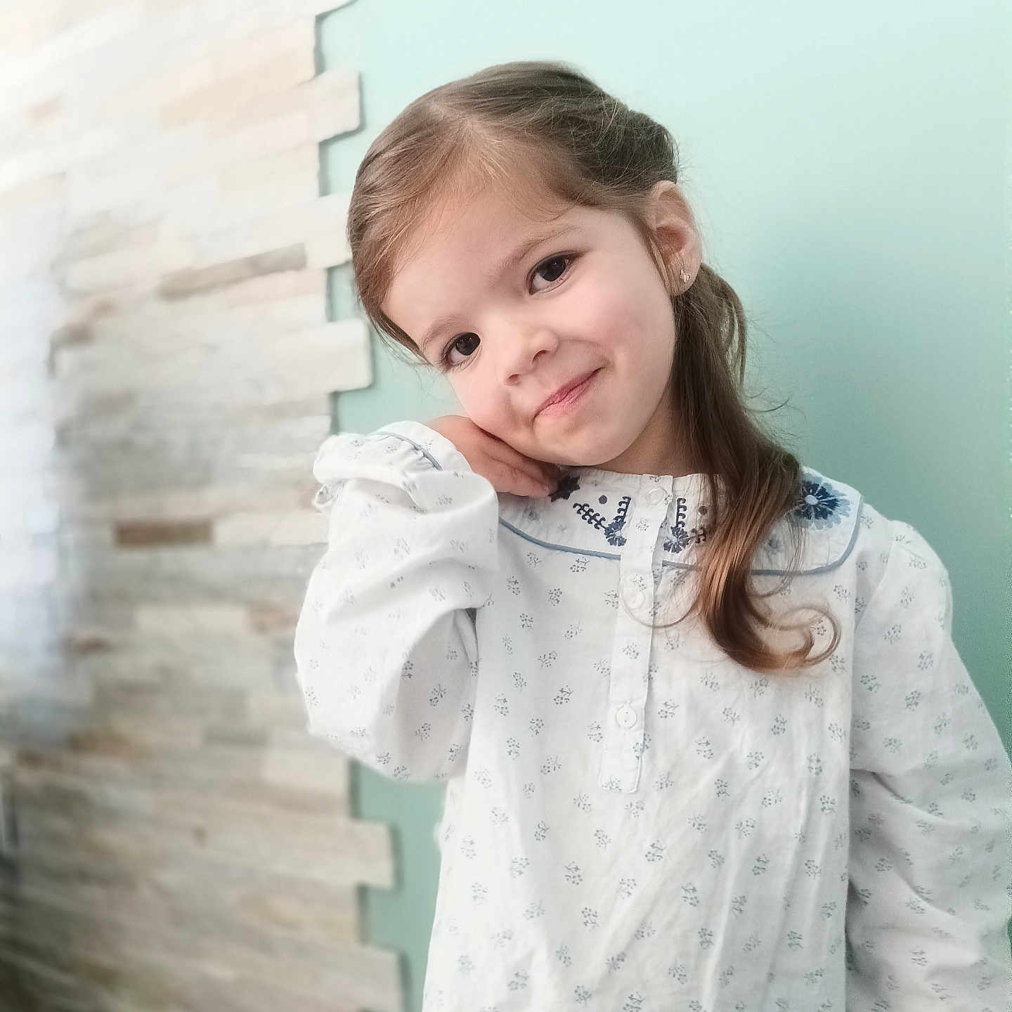 Lyana participe au concours pour gagner de l'argent avec cette photo : brick_wall, child, collar, cute, earring, eyes, girl, hand_on_cheek, happy, indoor, long_hair, pastel_wall, patterned_dress, portrait, posing, smile, soft_light, tilted_head, white_dress, young