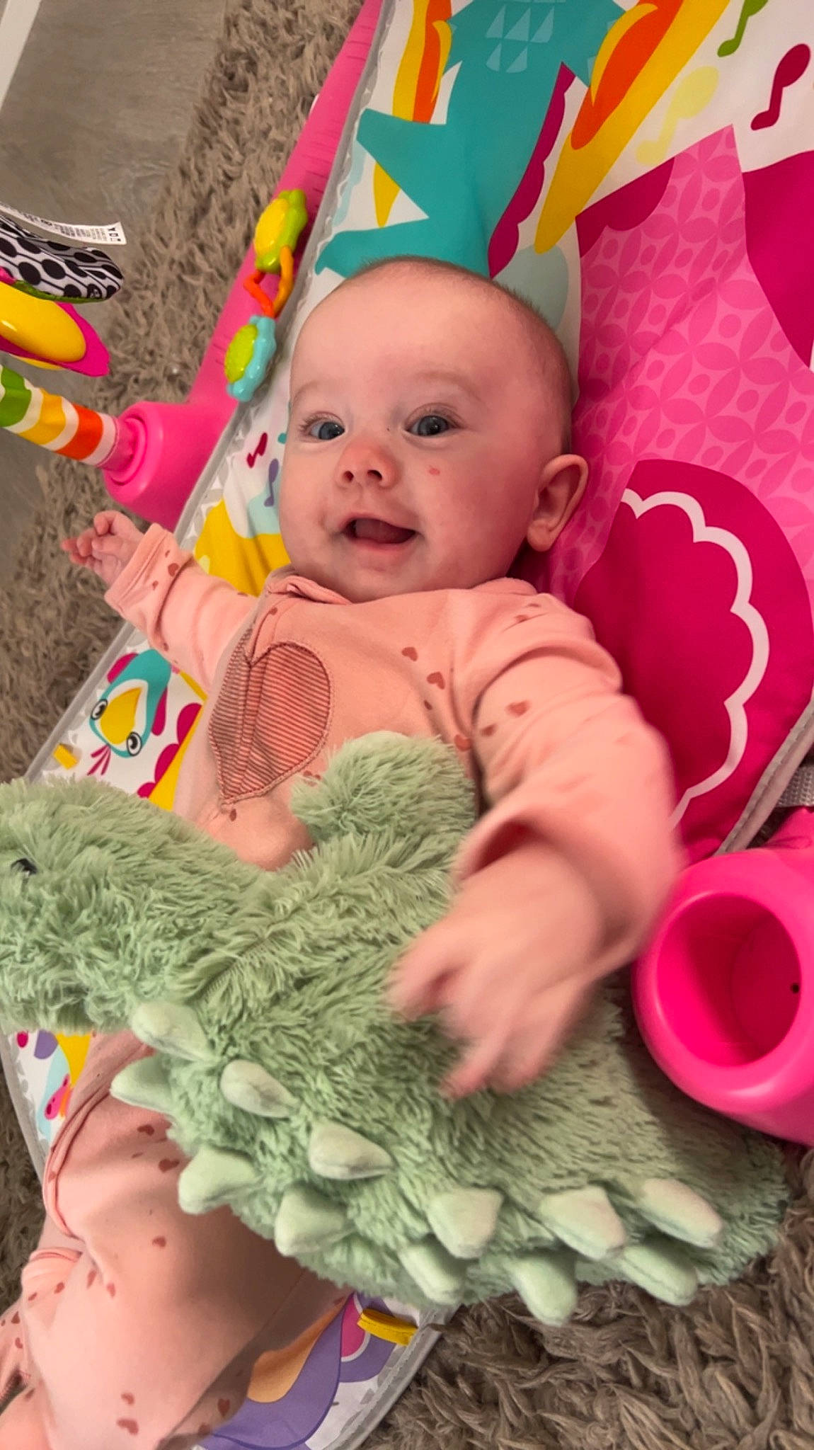 Annalise is registered to the contest to win money with this photo: baby, baby_playing_with_toys, baby_toddler_clothing, cheek, child, face, facial_expression, fun, green, happy, head, headgear, organ, person, pink, product, skin, sleeve, smile, textile