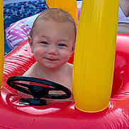 Cole joined the competition — help win amazing prizes! toddler, child, inflatable, pool, water, toy, steering_wheel, red, yellow, summer, smile, face, wet, outdoor, play, fun, baby, cute, expression, skin