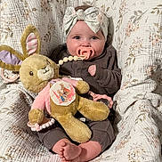 Amelia Nancyanne is registered to the contest to win money with this photo: baby, pacifier, headband, plush_toy, bunny, blanket, quilt, floral_pattern, clothing, infant, cute, indoors, child, smiling, foot, hand, soft_toy, portrait, cozy, warm