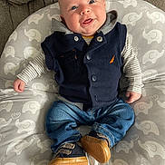 Bodhi is registered to the contest to win money with this photo: baby, smiling, infant, clothing, vest, jeans, shoes, striped_shirt, cushion, elephant_pattern, indoor, portrait, happy, cute, child, seated, cozy, casual, apparel, person