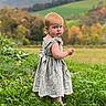child, toddler, girl, outdoor, field, grass, mountains, landscape, autumn, nature, dress, frilly_dress, blonde_hair, portrait, standing, serious_expression, scenery, rural, farmland, daylight