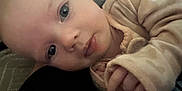 Taliyah is registered to the contest to win money with this photo: baby, child, face, closeup, blue_eyes, cozy_clothing, hand, infant, lying_down, soft_texture, skin, portrait, cute, indoor, young_child, expression, sleepwear, human, small_fingers, resting