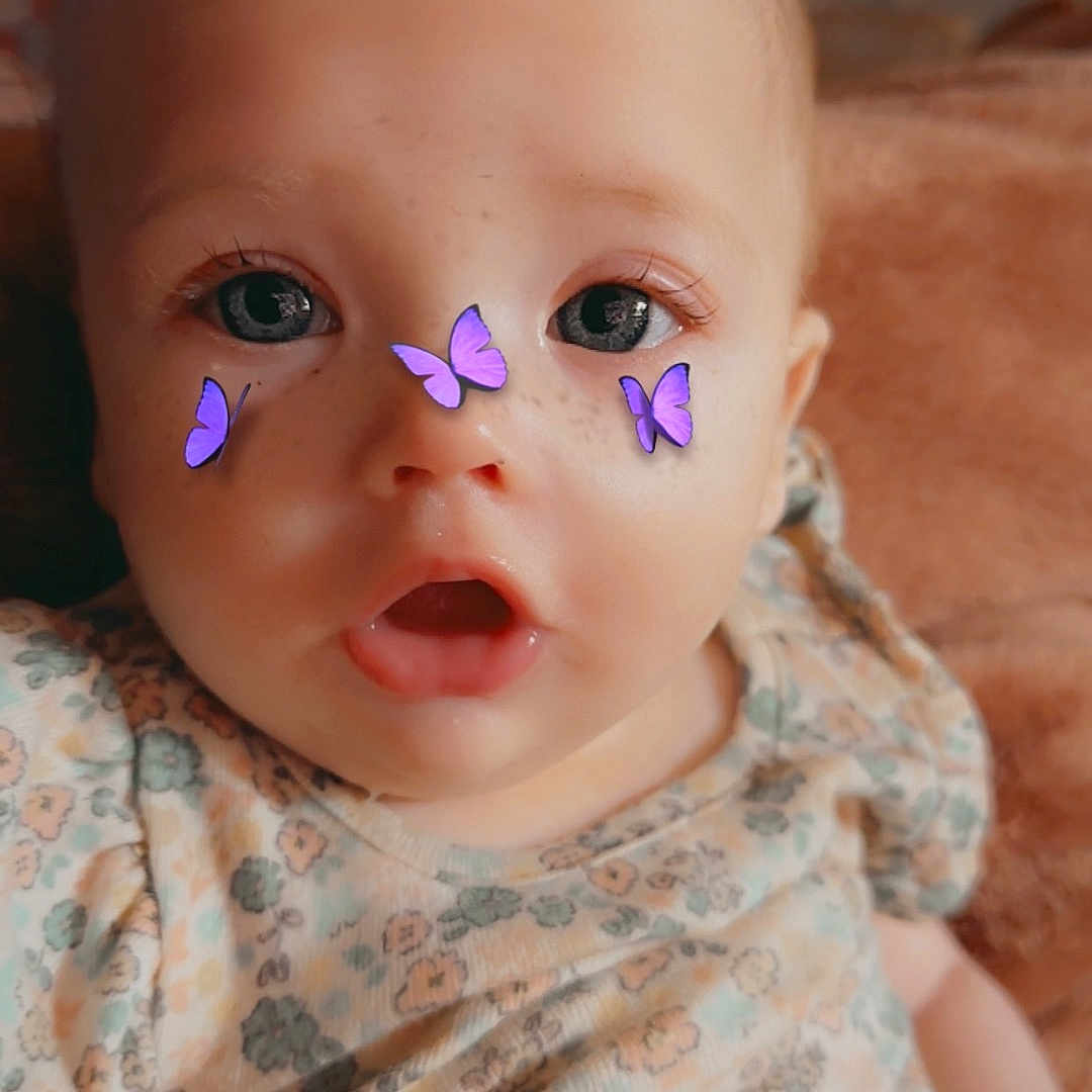 Taliyah is registered to the contest to win money with this photo: baby, child, closeup, clothing, cute, expression, eyes, face, filter, floral_pattern, head, indoor, infant, mouth, portrait, purple_butterflies, sitting, skin, soft_light, young