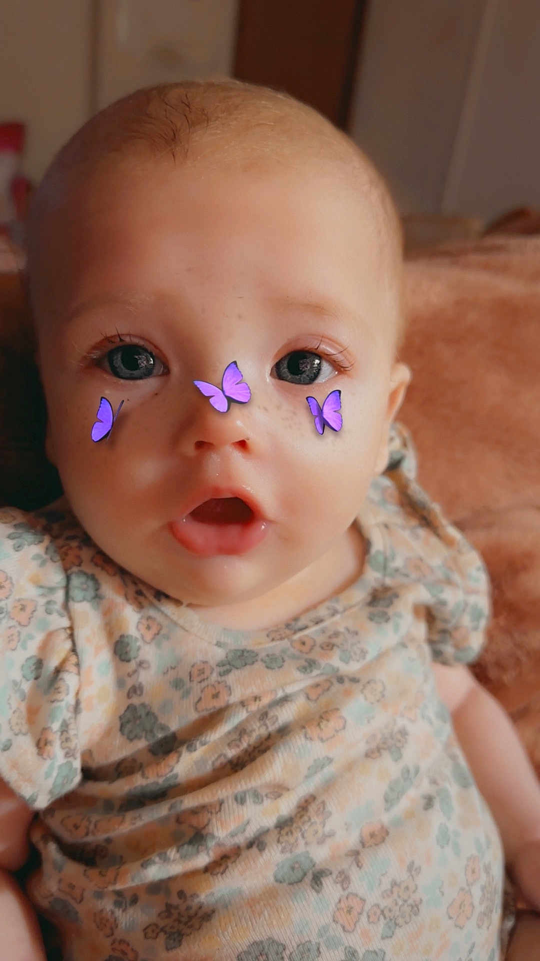 Taliyah is registered to the contest to win money with this photo: baby, infant, child, face, eyes, mouth, clothing, floral_pattern, purple_butterflies, filter, closeup, portrait, cute, expression, soft_light, indoor, skin, head, sitting, young