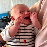 Noham a rejoint le concours — aidez-le/la à gagner de superbes lots ! baby, smiling, striped_clothing, infant, person, happy, cute, hand, face, adult, holding, indoors, sleeve, blue, white, red, skin, portrait, child, closeup