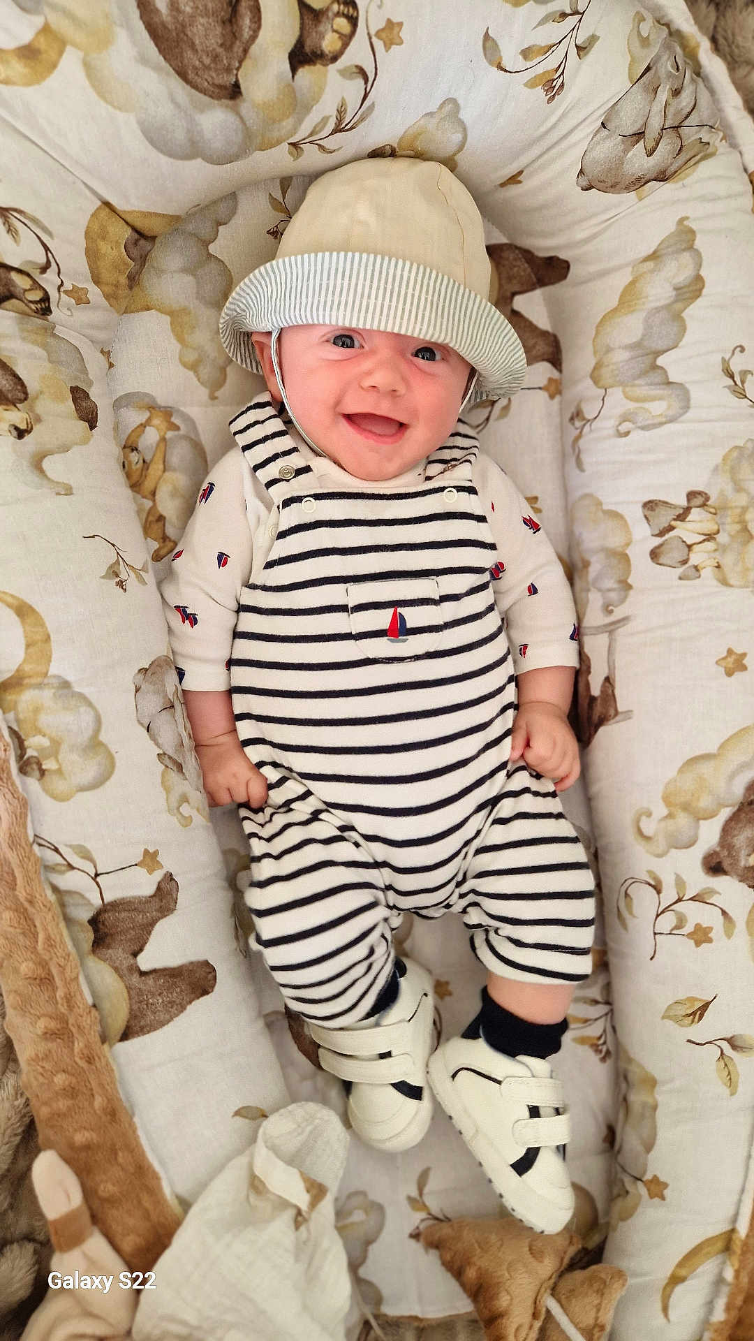 Noham a rejoint le concours — aidez-le/la à gagner de superbes lots ! baby, smiling, hat, striped_clothing, shoes, baby_nest, cozy, infant, happy, person, cute, child, indoors, fabric, pattern, soft_toys, comfortable, portrait, newborn, clothing