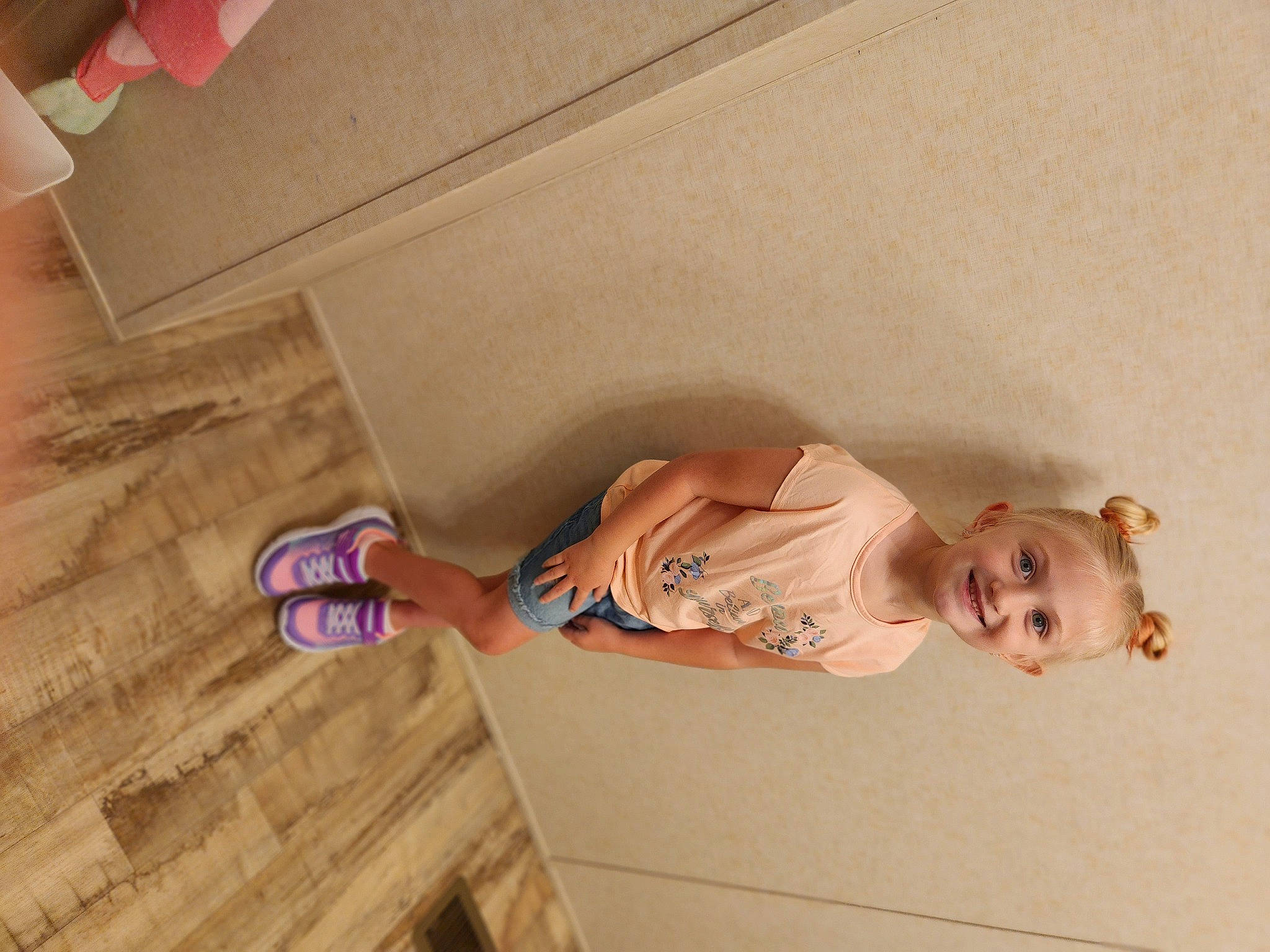 Adaleigh is registered to the contest to win money with this photo: ceiling, child, dress, finger, floor, flooring, foot, fun, hardwood, human_leg, joy, knee, peach, person, pink, room, sandal, textile, thigh, toddler