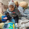 Djawël participe au concours pour gagner de l'argent avec cette photo : baby, beanie, blanket, child, colorful, curious_expression, face, floor, indoor, jacket, pillow, playroom, plush_toy, portrait, sitting, socks, soft_toy, stuffed_animal, toddler, toy