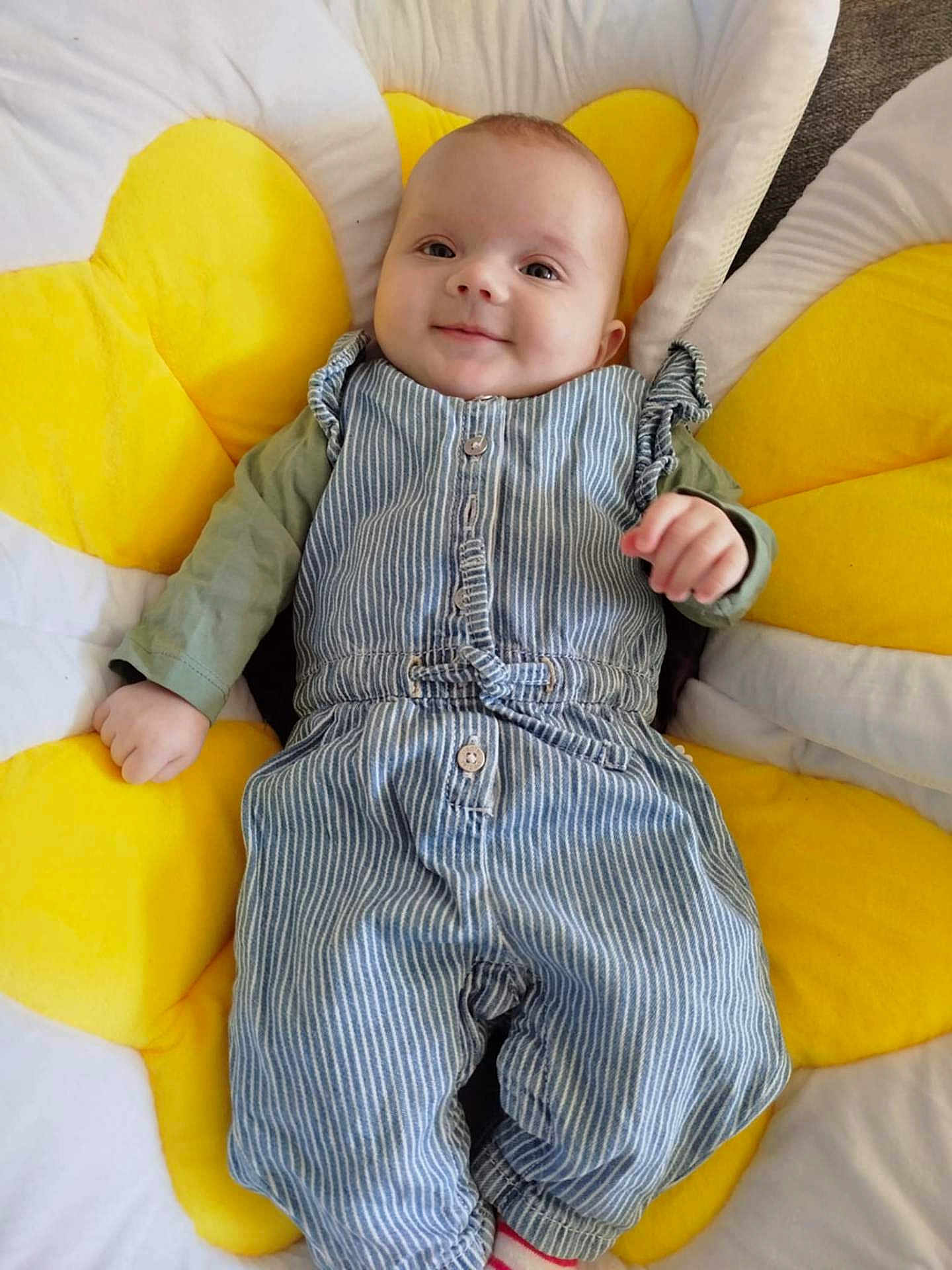 Naeily a rejoint le concours — aidez-le/la à gagner de superbes lots ! baby, child, smile, face, overalls, striped_clothing, cushion, yellow, flower_shape, indoor, happy, cute, infant, person, portrait, clothing, relaxing, head, hand, comfort