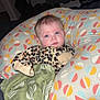 baby, infant, portrait, pillow, patterned_pillow, blanket, green_blanket, onesie, leopard_print, blue_eyes, cheeks, hair, indoor, flash, bed, sleepwear, expression, lying_down, curtains, cute