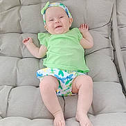 Emma a rejoint le concours — aidez-le/la à gagner de superbes lots ! baby, barefoot, child, cushion, cute, green_clothing, happy, headband, infant, legs, outdoor_furniture, person, plush, portrait, relaxing, resting, seat, skin, smiling, young_child